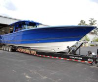 large blue and white hydrasport boat on a trailer attached to the back of a black pick up truck