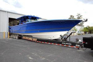 large blue and white hydrasport boat on a trailer attached to the back of a black pick up truck