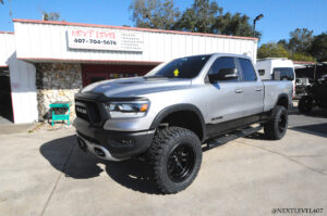 Next Level Silver Dodge Ram Vertex Rough County Suspension and Toyo Open Country Tire Install Orlando Store Front Profile